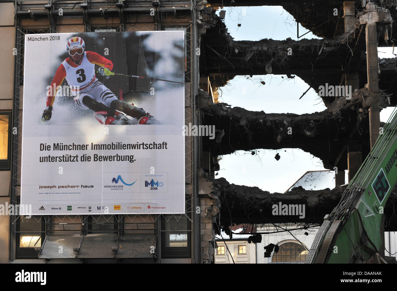 A large advertisement with the caption 'Munich real estate bank supports the German application for hosting the Olympic Games in 2018' hangs on a house that is in the process of demolition in Munich, Germany, 4 February 2011. Is this supposed to be ironic? Photo: Peter Kneffel Stock Photo