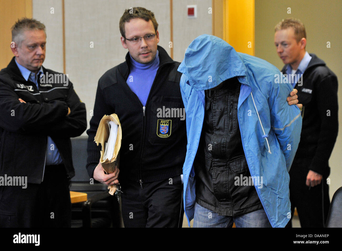 The 35-year-old Eritrean defendant (C-R) hides his face as he arrives for hi strial at district court Frankfurt Main, Germany, 09 February 2011. The defendant is charged with manslaughter, he is accused of having stabbed NIgerian Emeka Okoronkwo to death on 02 May 2010. Okoronkwo had helped two women who felt molested by the defendant and his mate. Photo: MARIUS BECKER Stock Photo