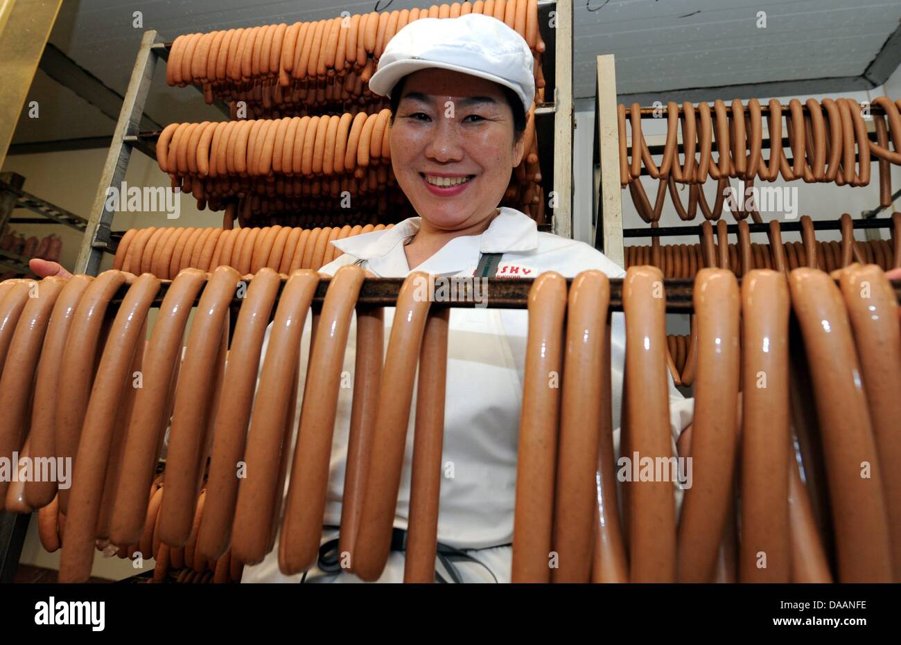 Korean Kui Kyung Lee smiles next to sausages in Bredstedt, Germany, 31 January 2011. Lee leads a facility for challenged people in South Korea and produces there about half-a-dozen kinds of sausages from pork, veal, and beef. Currently, Lee serves an internship at a northern German sausage producer. Photo: Carsten Rehder Stock Photo