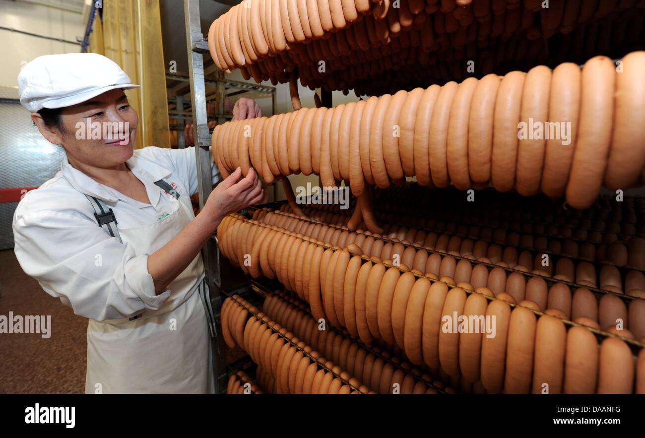 Korean Kui Kyung Lee smiles next to sausages in Bredstedt, Germany, 31 January 2011. Lee leads a facility for challenged people in South Korea and produces there about half-a-dozen kinds of sausages from pork, veal, and beef. Currently, Lee serves an internship at a northern German sausage producer. Photo: Carsten Rehder Stock Photo