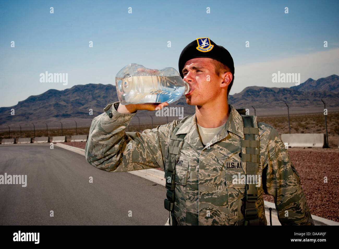 Airman 1st Class Jeffrey Albright, 99th Security Forces Squadron journeyman, drinks water in front of the Area 2 gate July 2, 2013, at Nellis Air Force Base, Nev. Working in near-record temperatures as high as 117 degrees, Airmen must hydrate frequently i Stock Photo