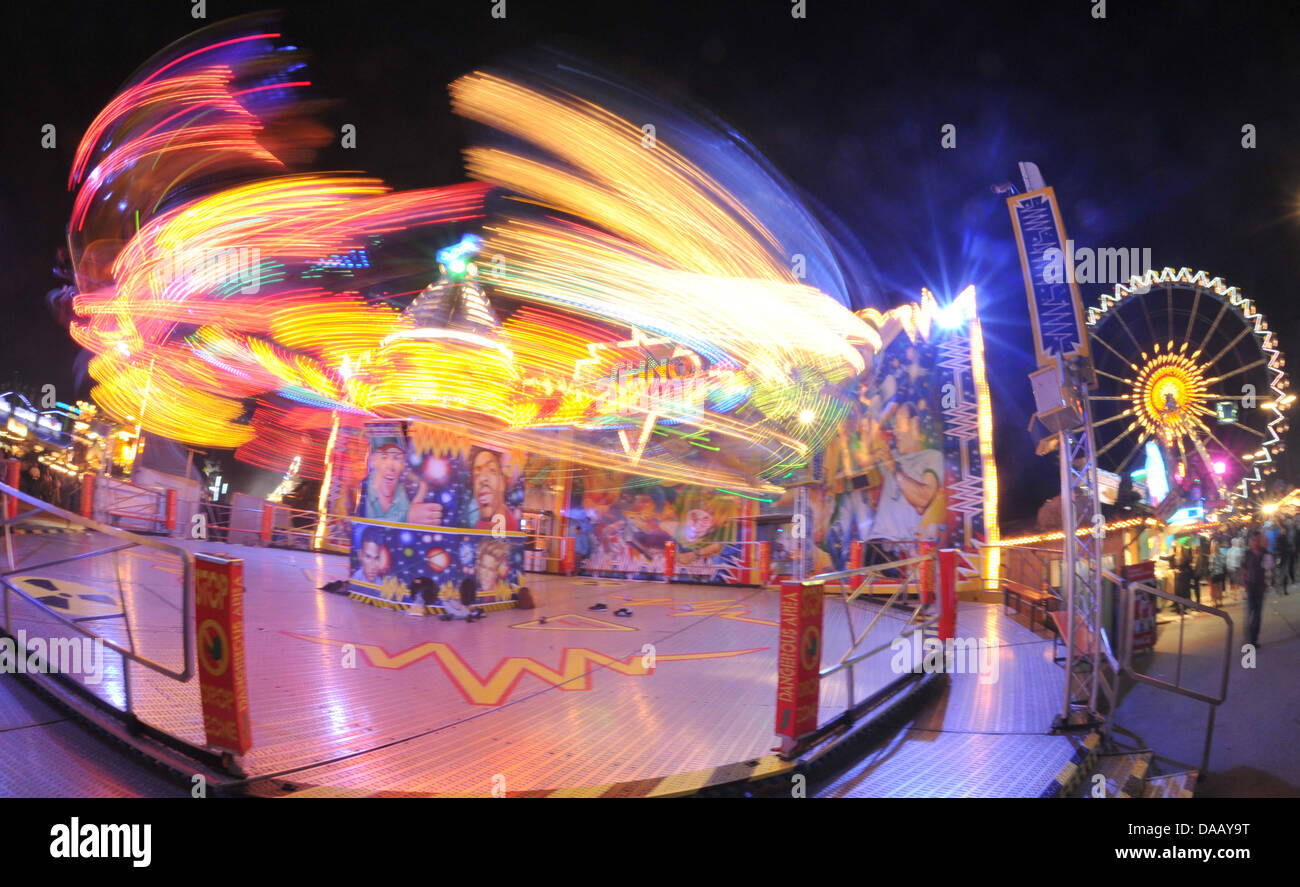 The giant Ferris wheel and other rides are seen at night at Oktoberfest ...