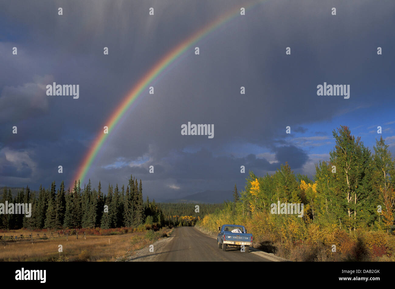Tagish, Yukon, Canada, stormy sky, rainbow, rainbow, road, blue pickup, rain, low sun Stock Photo