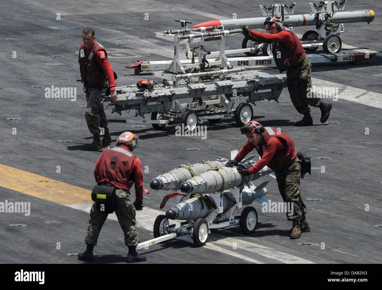Aviation ordnancemen transport ordnance across the flight deck of the aircraft carrier USS Nimitz (CVN 68). The Nimitz Carrier Strike Group is deployed to the U.S. 5th Fleet area of responsibility conducting maritime security operations, theater security Stock Photo