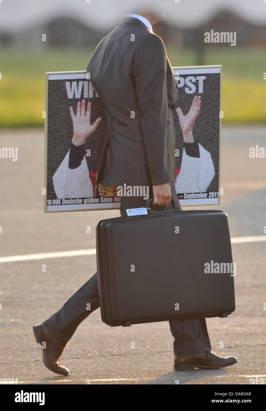 A man holding his suitcase and a portrait picture of Pope Benedict XVI at the Black Forest airport in Lahr, Germany, 25 September 2011. The head of the Roman Catholic Church is visiting Germany from 22-25 September 2011. Foto: Uli Deck dpa/lsw Stock Photo
