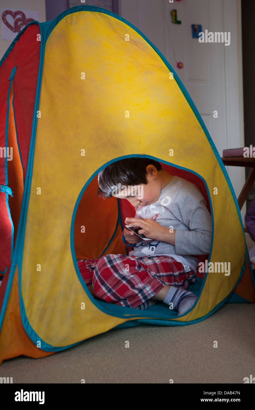 Boy plays computer games on a touchscreen mobile device Stock Photo
