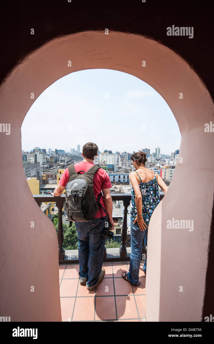 Couple looking at downtown skyline cityscape of Lima from the bell tower of the Church and Convent of Santo Domingo, Lima, Peru. Stock Photo