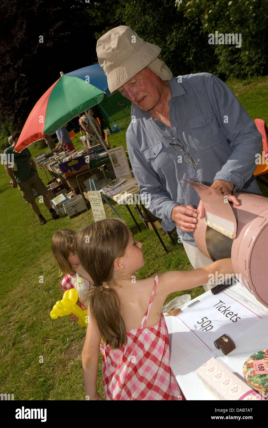 6 year old girl trying her luck at the Tombola at a summer fete, East Meon, Hampshire, UK. Stock Photo