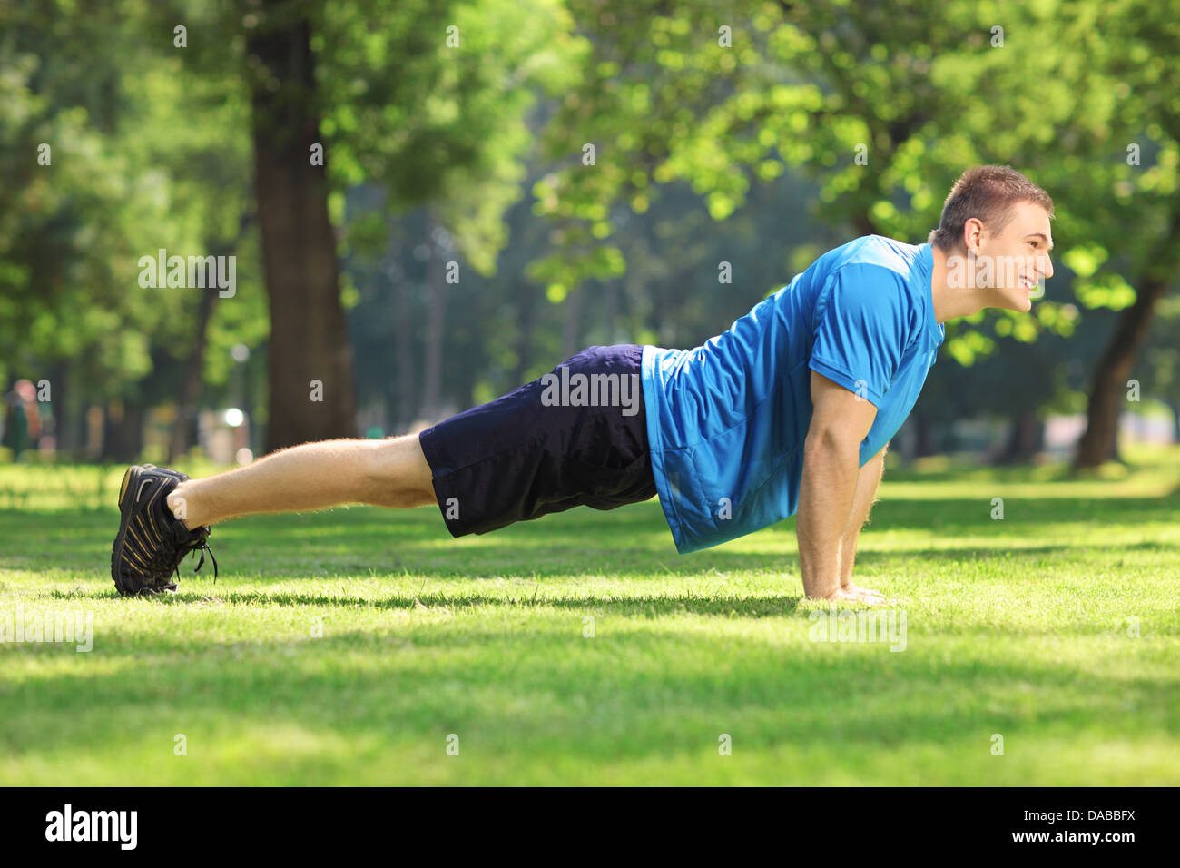 Young handsome sportsman exercising in a park Stock Photo