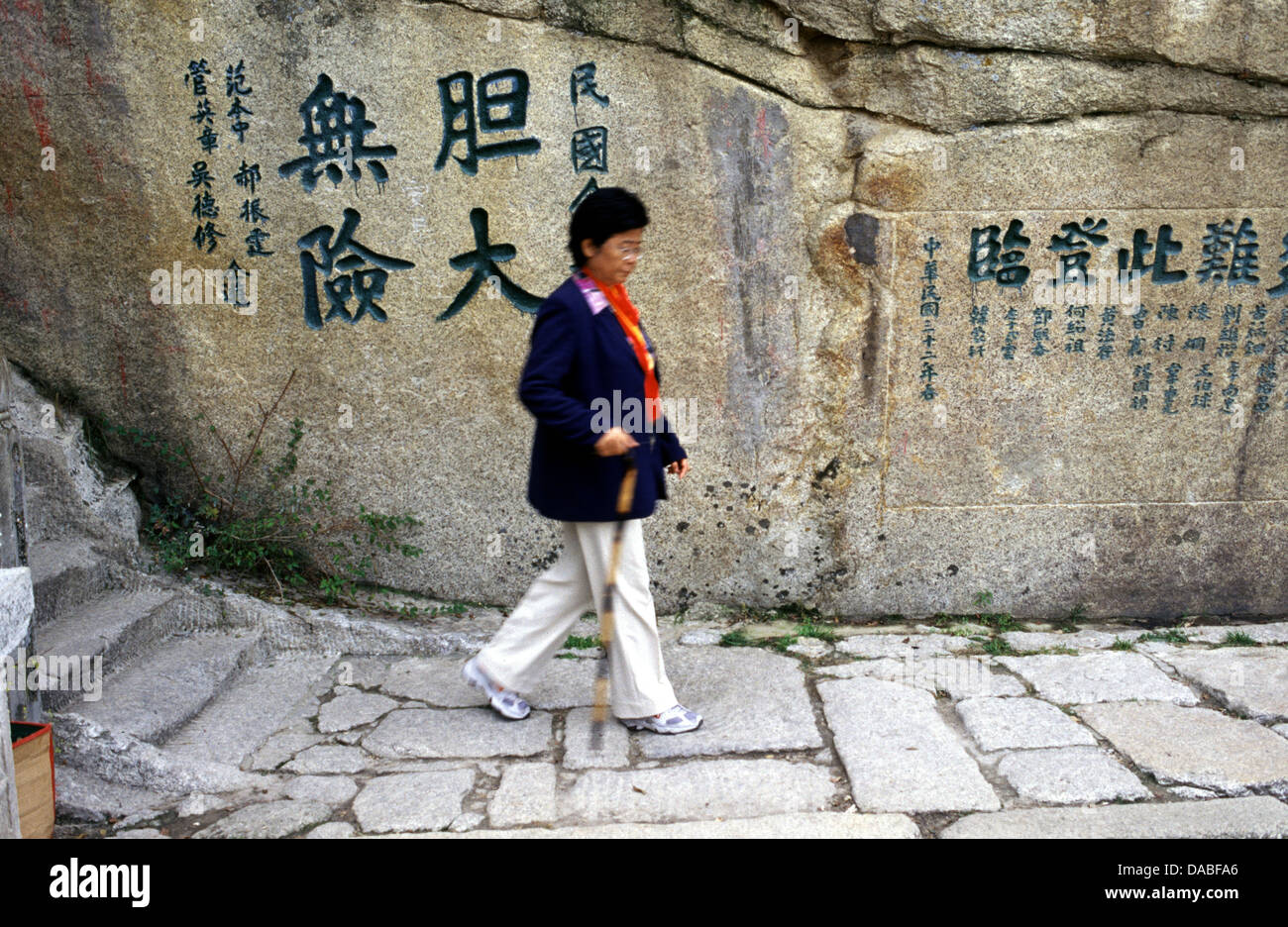 Chinese woman walking with a stick in Hua Shan mountain located near the city of Huayin in Shaanxi province China. Mount Hua is the western mountain of the Five Great Mountains of China, and has a long history of religious significance. Stock Photo