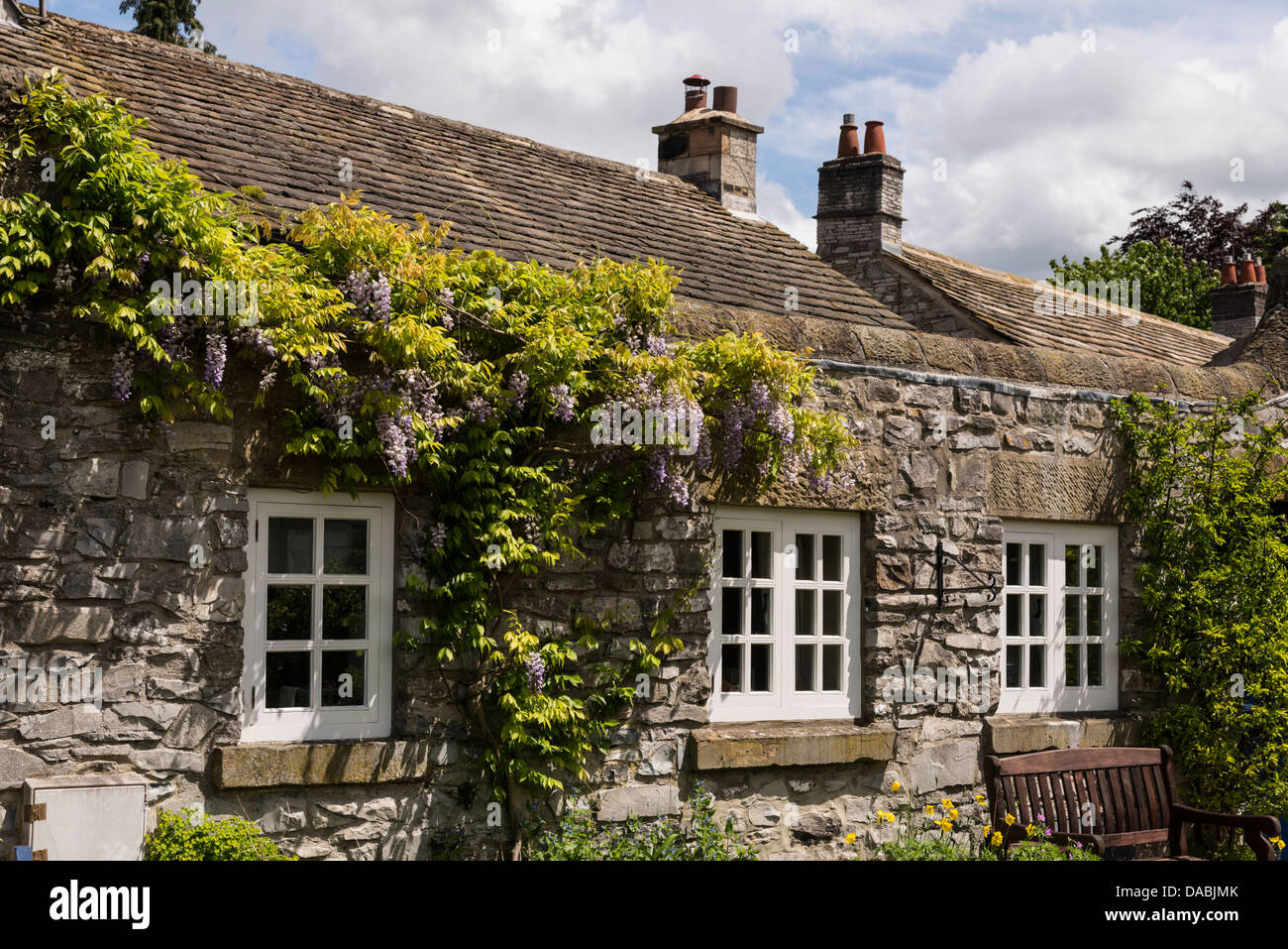 Stone Cottage With White Window Frames Covered In Climbing