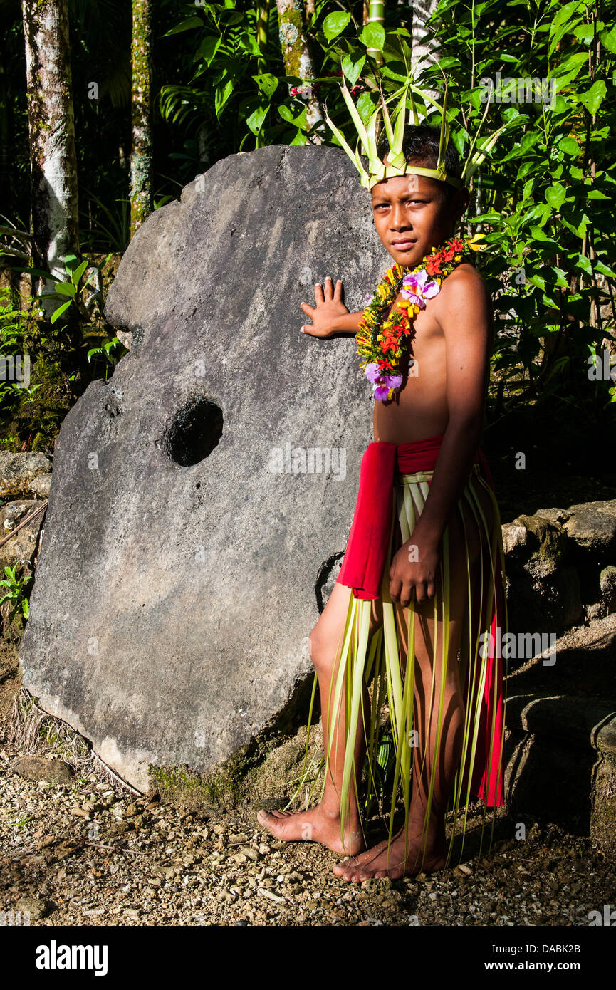 Boy in traditional dress on the island of Yap standing by a huge stone money, Federated States of Micronesia, Caroline Islands Stock Photo