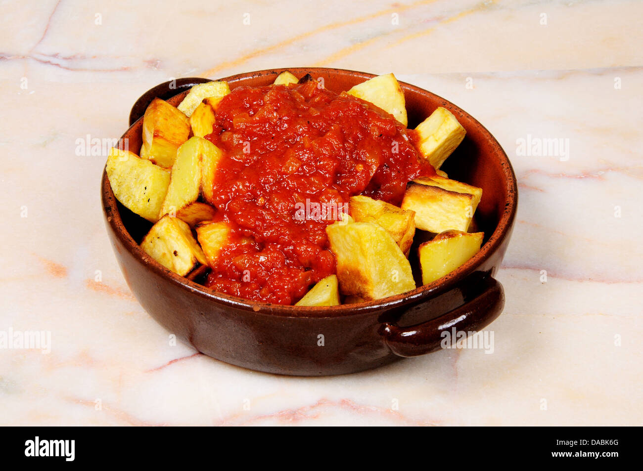 Spanish tapas of Patatas Bravas (Chipped potatoes in spicy tomato sauce). Stock Photo