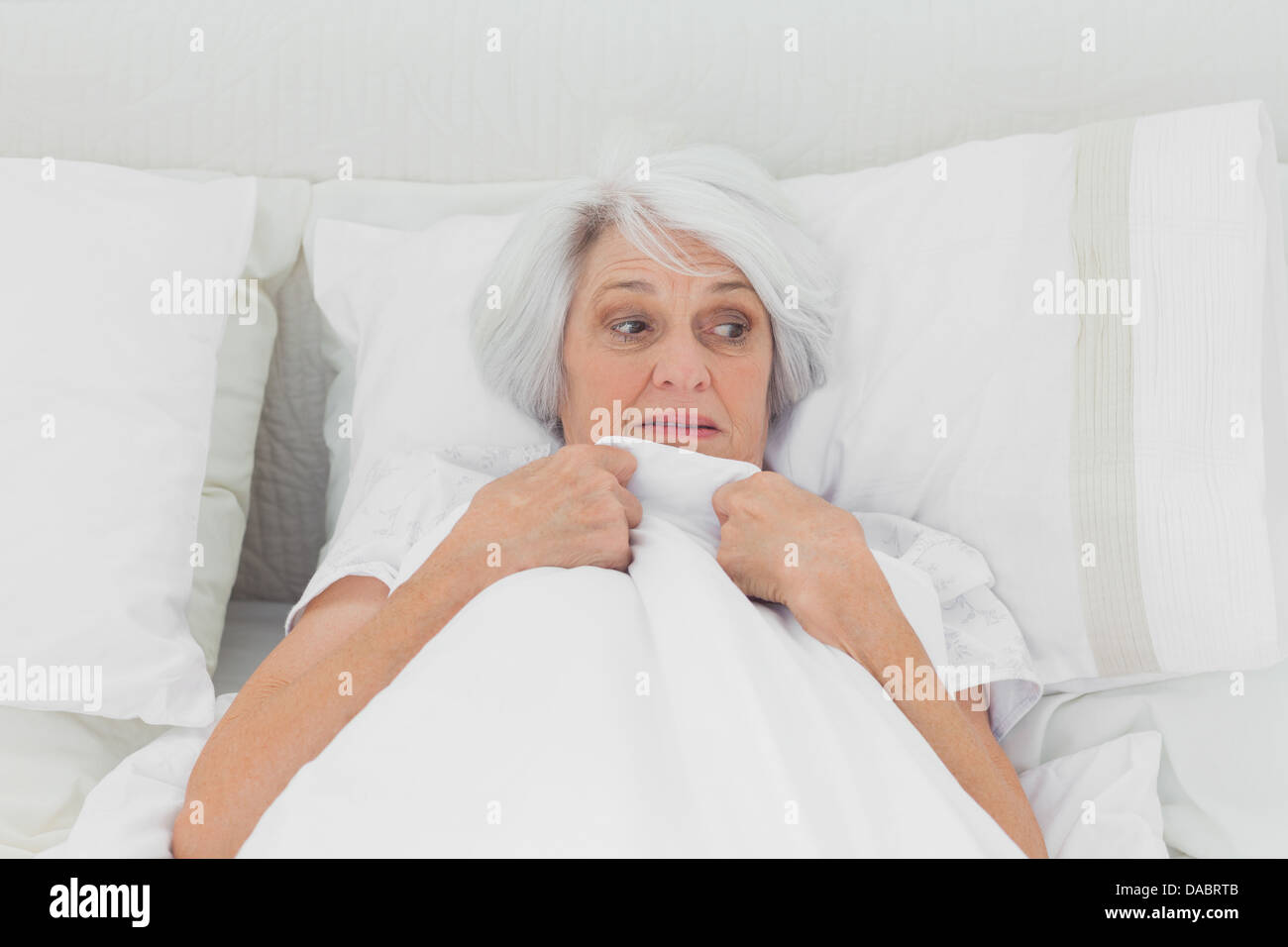 Fearful woman clutching her quilt Stock Photo