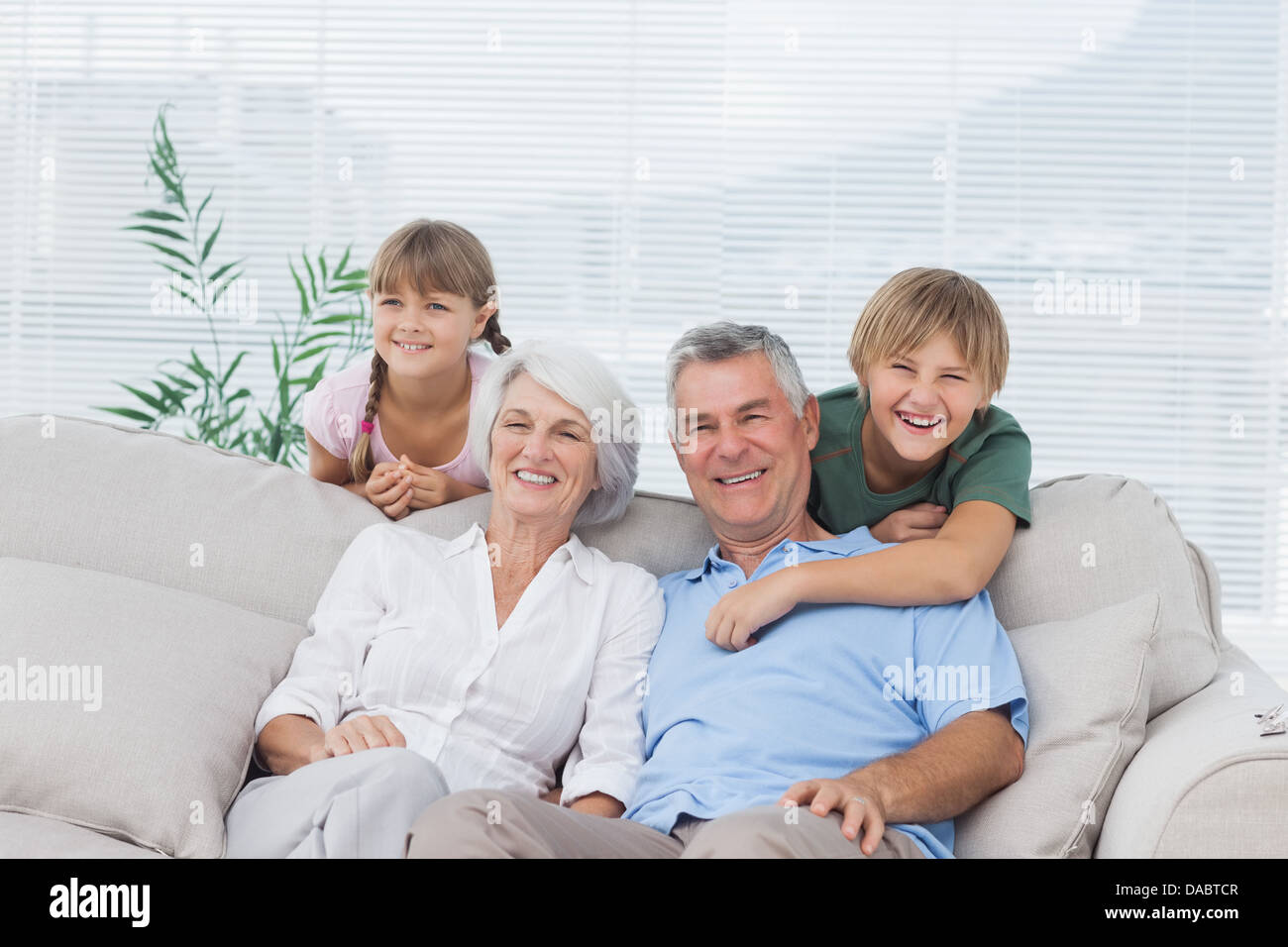Grandchildren and grandparents sitting on couch Stock Photo
