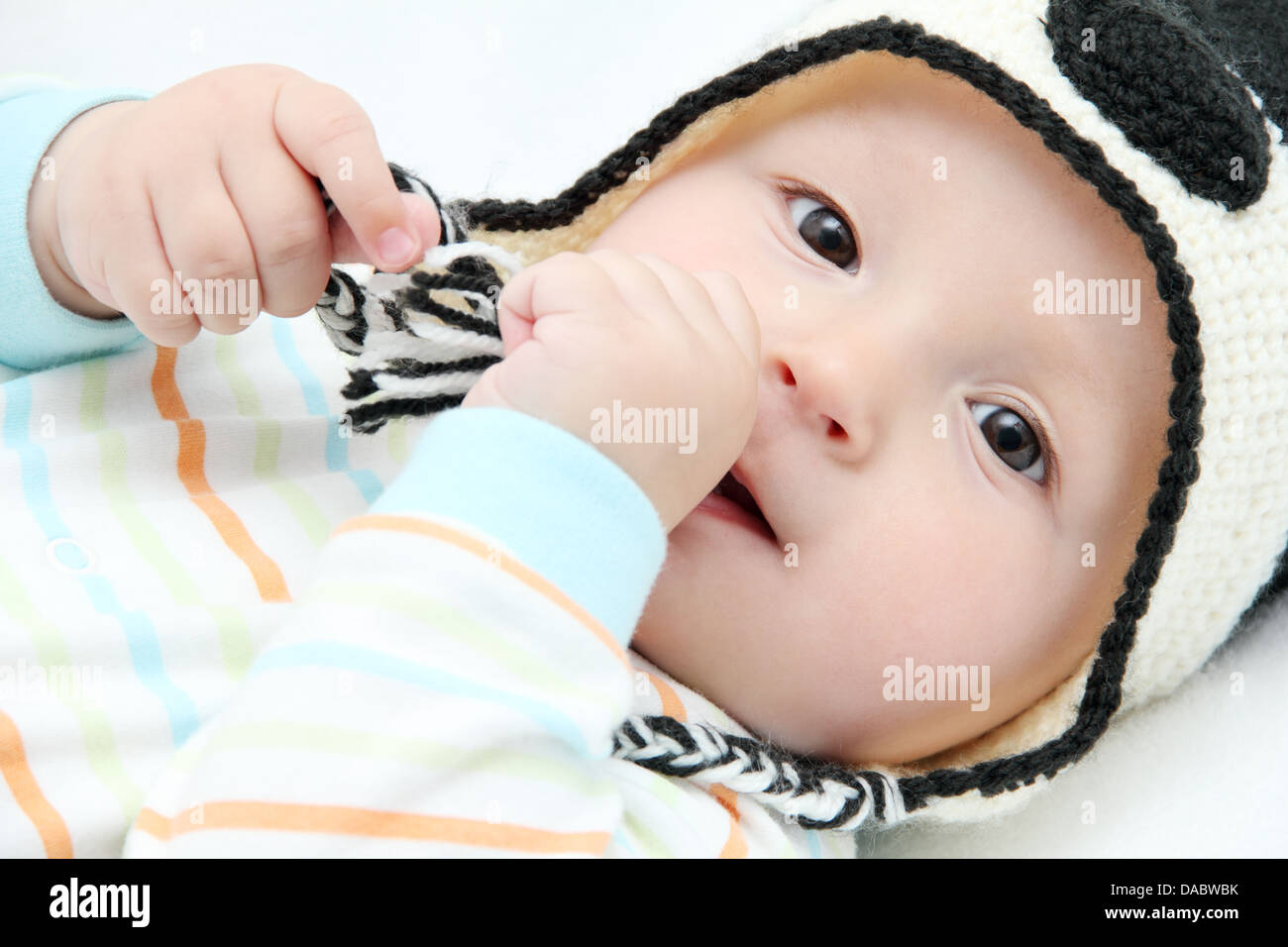 Happy baby lies on back on white bed Stock Photo