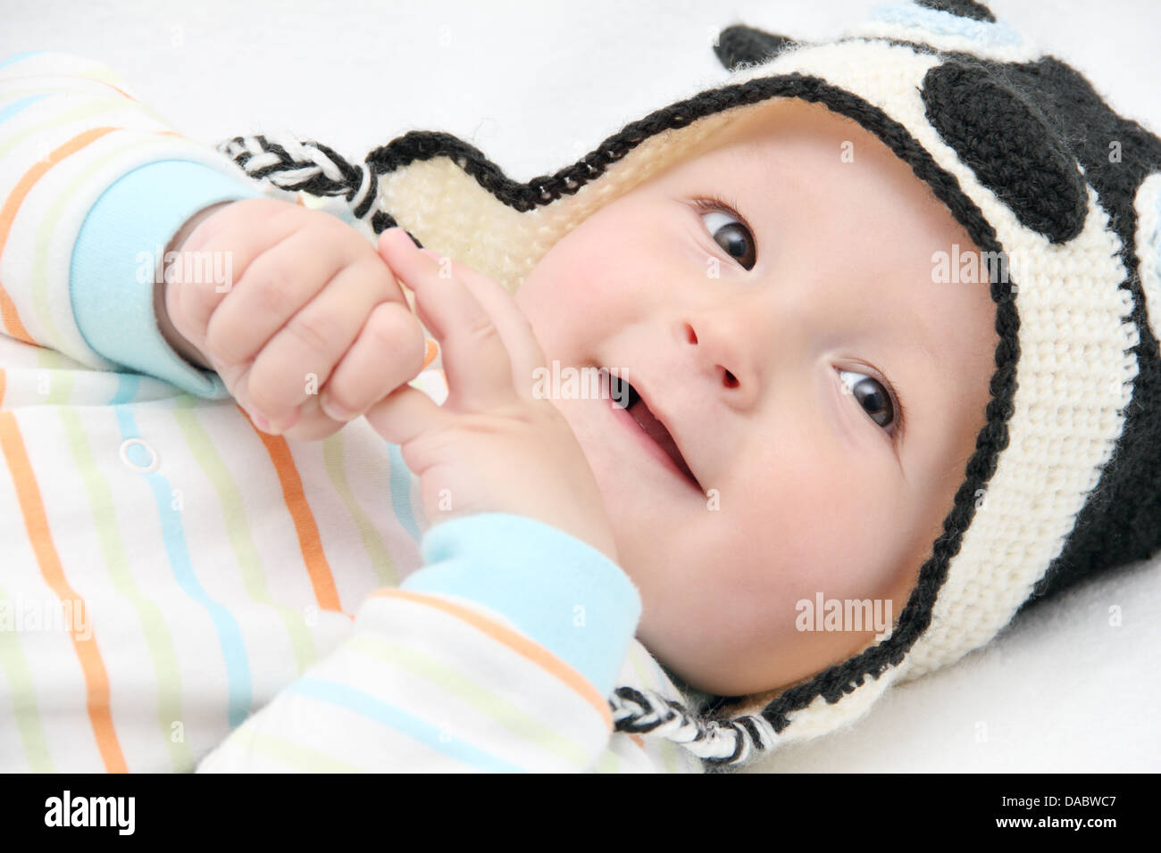 smiling baby lies on back on white bed Stock Photo