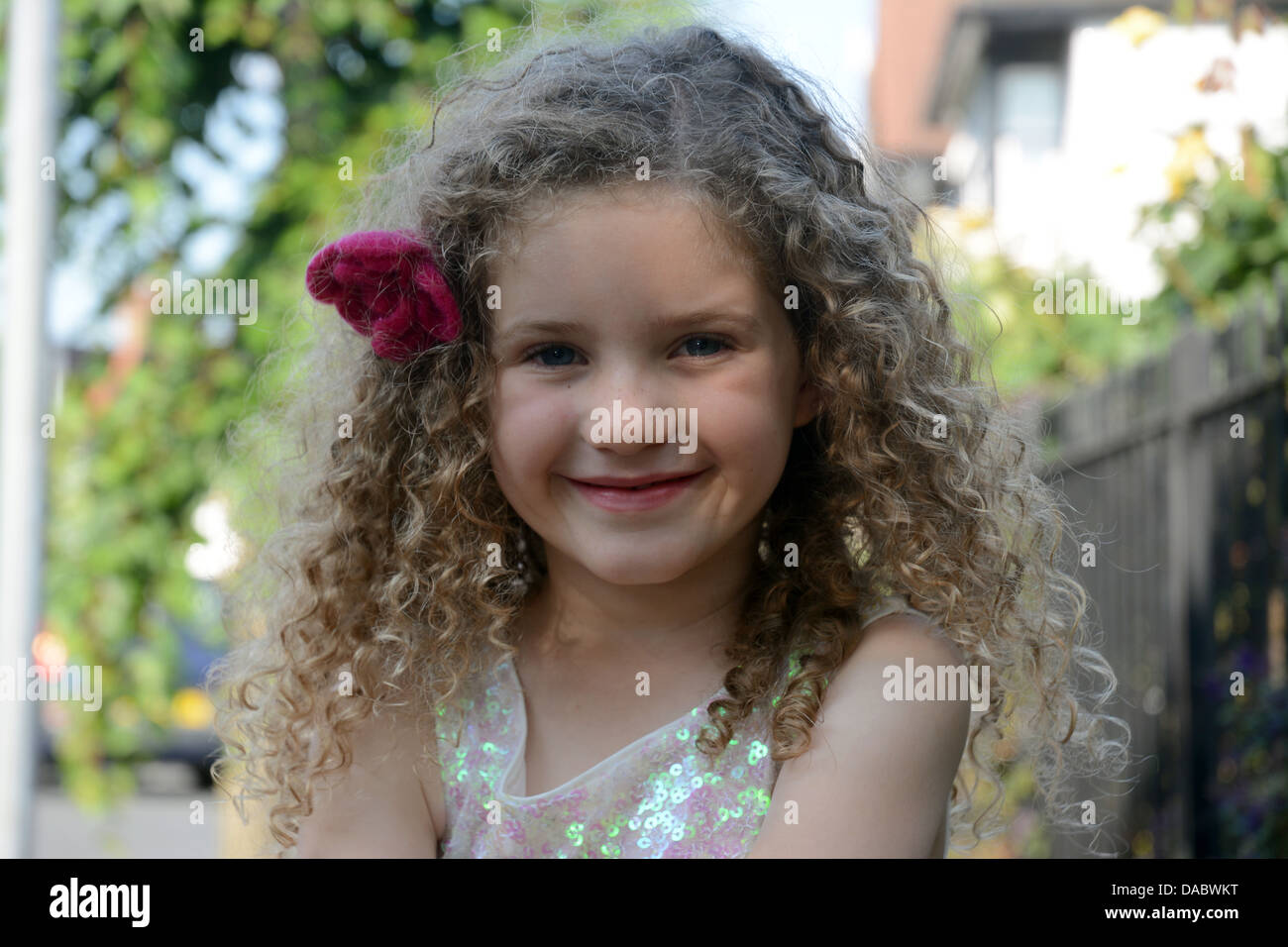 A pretty five year old girl with curly hair smiles into the camera Stock Photo