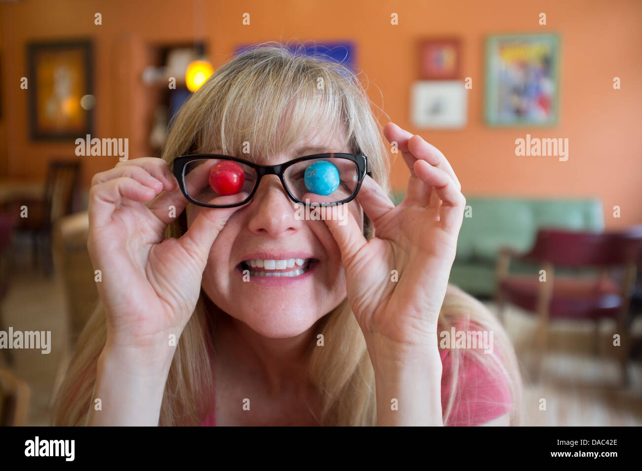 Woman holding colored, big gum balls in front of her eyes. Stock Photo