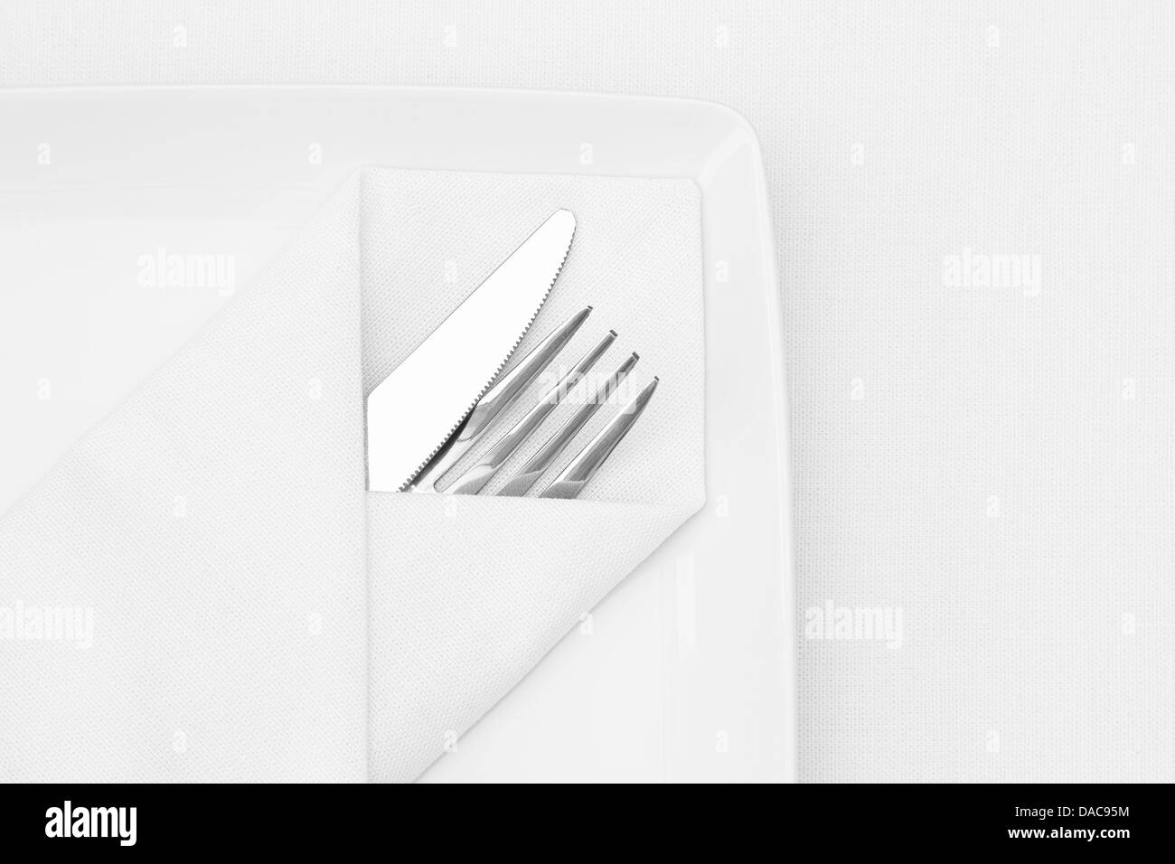 Place setting, white plate with cutlery and white napkin Stock Photo