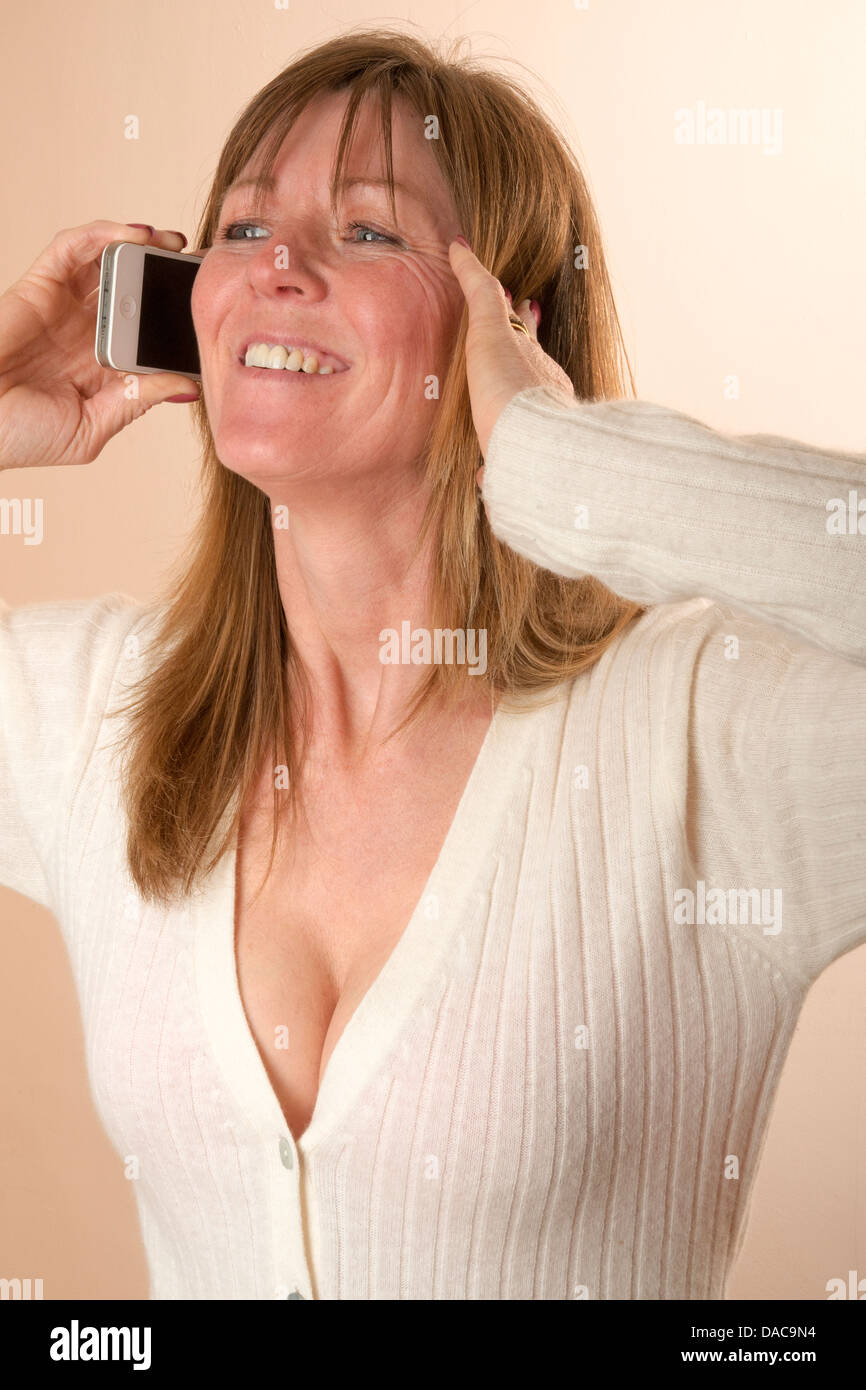 Woman answering a mobile phone call and having difficulty in hearing and has a finger in her ear Stock Photo
