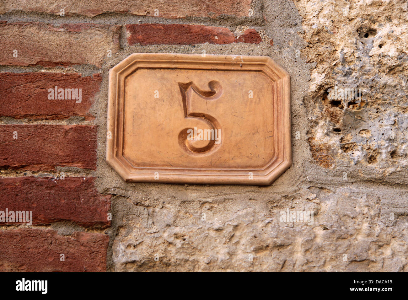 Street number five out of clay on a house in Tuscany in San Gimignano Stock Photo