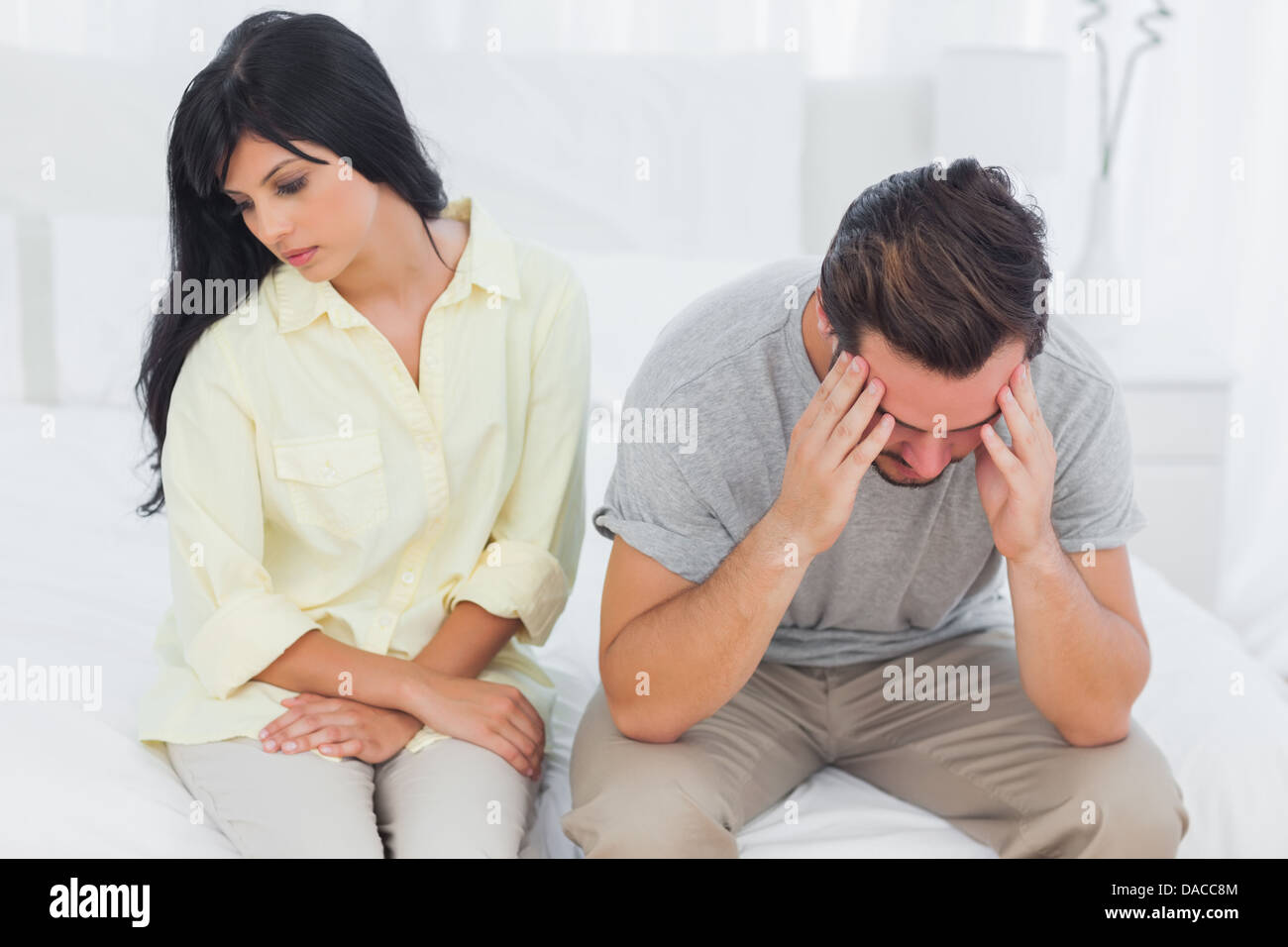 Woman sulking with boyfriend looking down during a fight Stock Photo