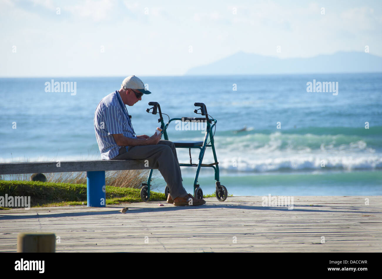 Man sat looking out to the Ocean on a warm sunny day. Stock Photo