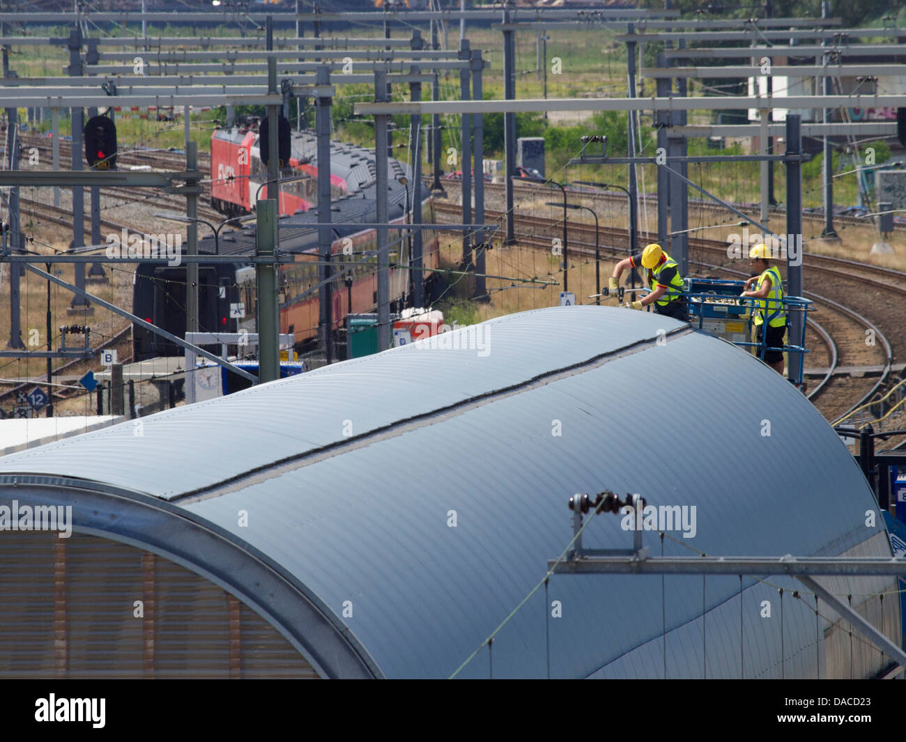 Men working on the roof of Breda central station, with Fyra train leaving for Amsterdam. the Netherlands Stock Photo