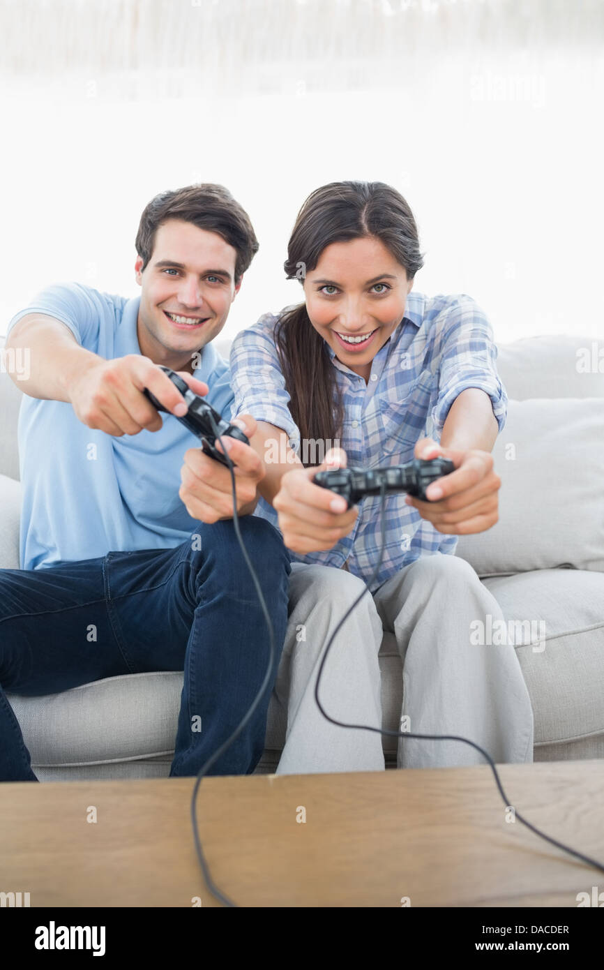 Portrait of a couple playing video games on the couch Stock Photo - Alamy