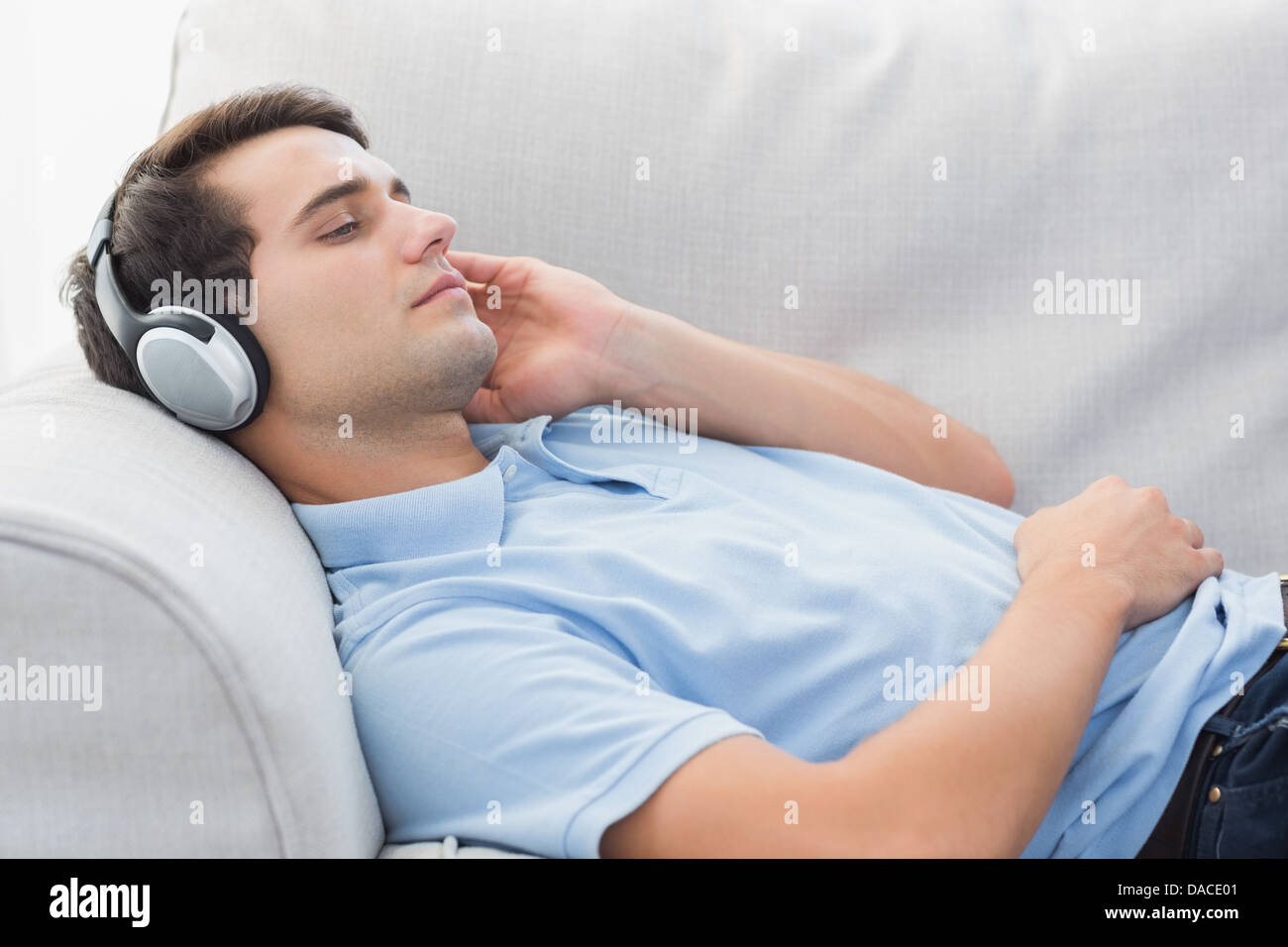 Man enjoying music lying on a couch Stock Photo Alamy