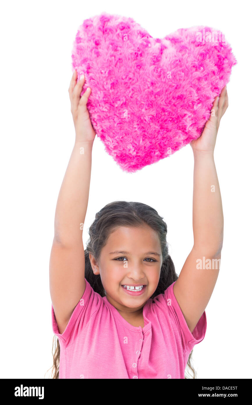 Smiling little girl holding cushion in the shape of a heart Stock Photo