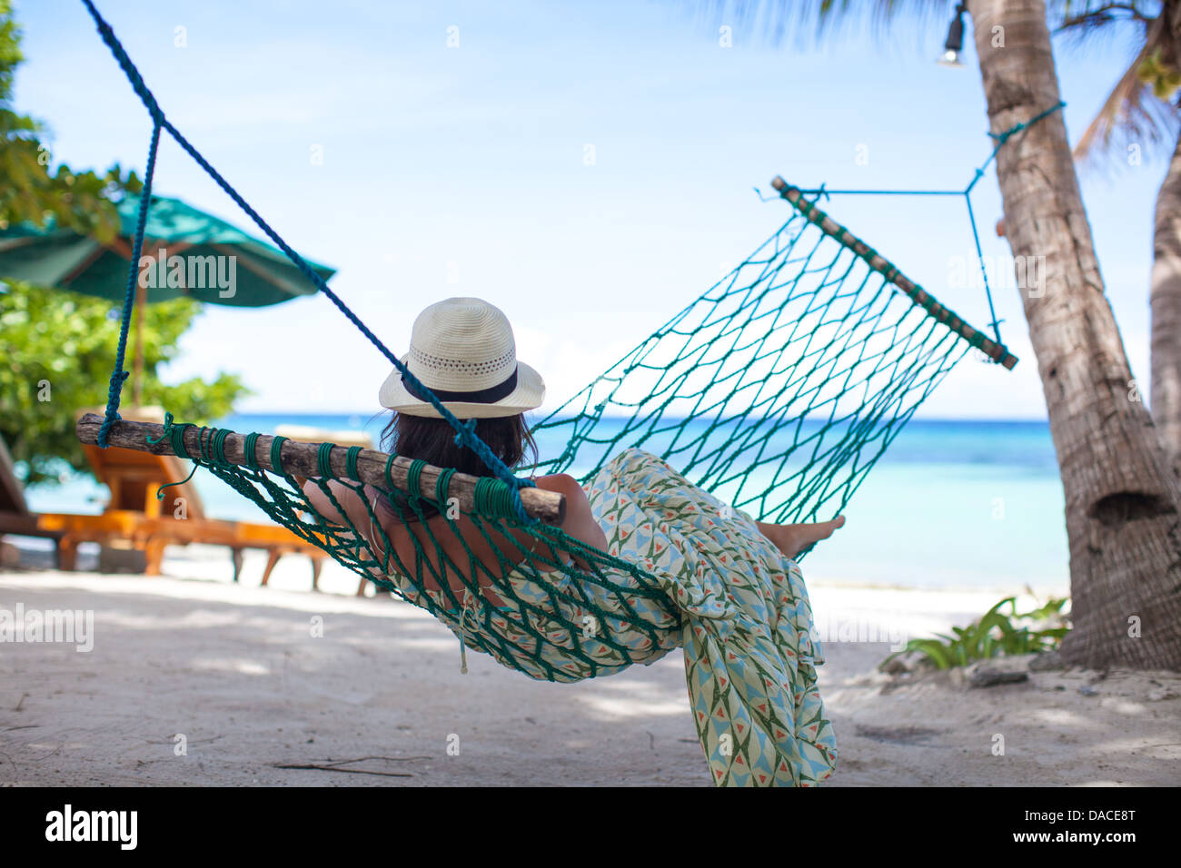 woman-in-hat-lying-in-hammock-in-tree-s-shadow-on-a-beach-stock-photo