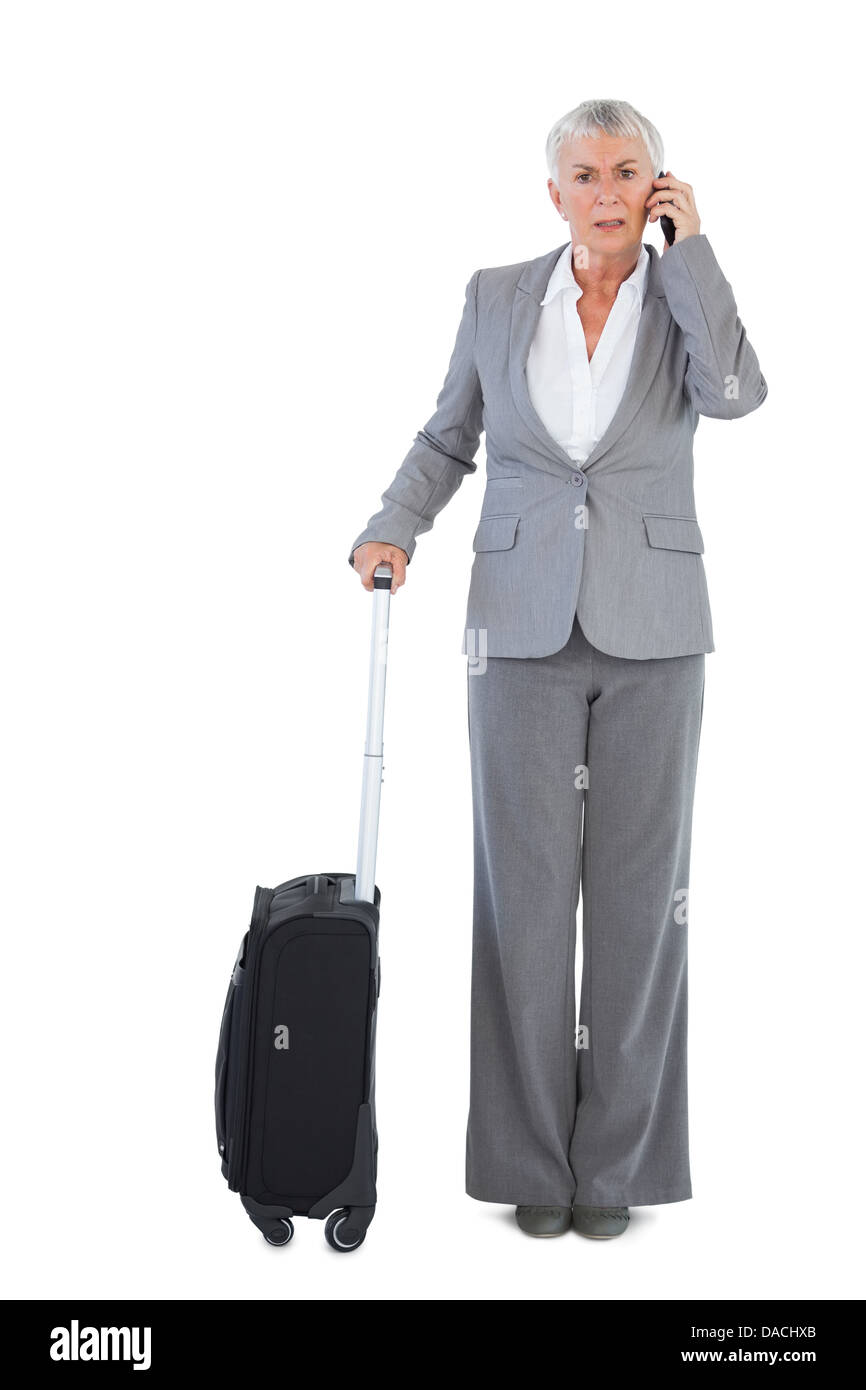 Serious businesswoman with her luggage and calling someone Stock Photo