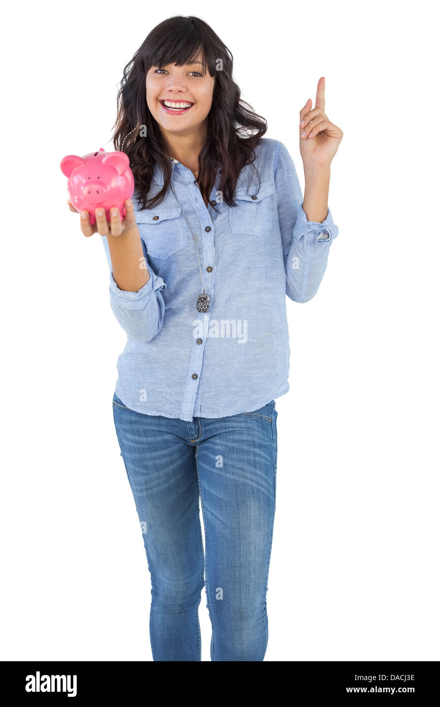 Smiling young woman with piggy bank pointing her finger Stock Photo - Alamy