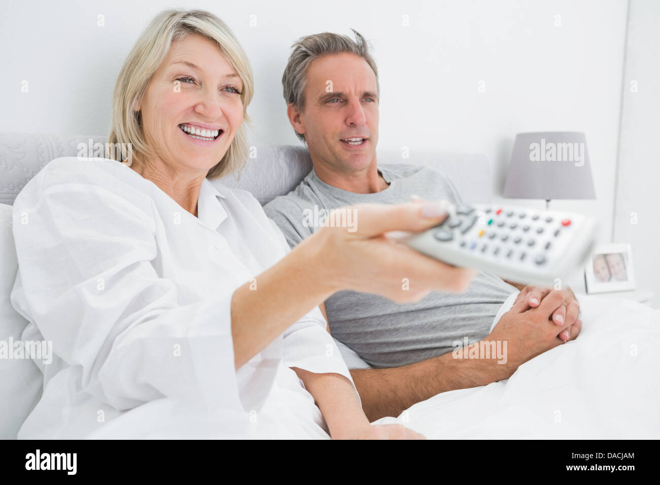 Happy couple watching tv in bed Stock Photo Alamy