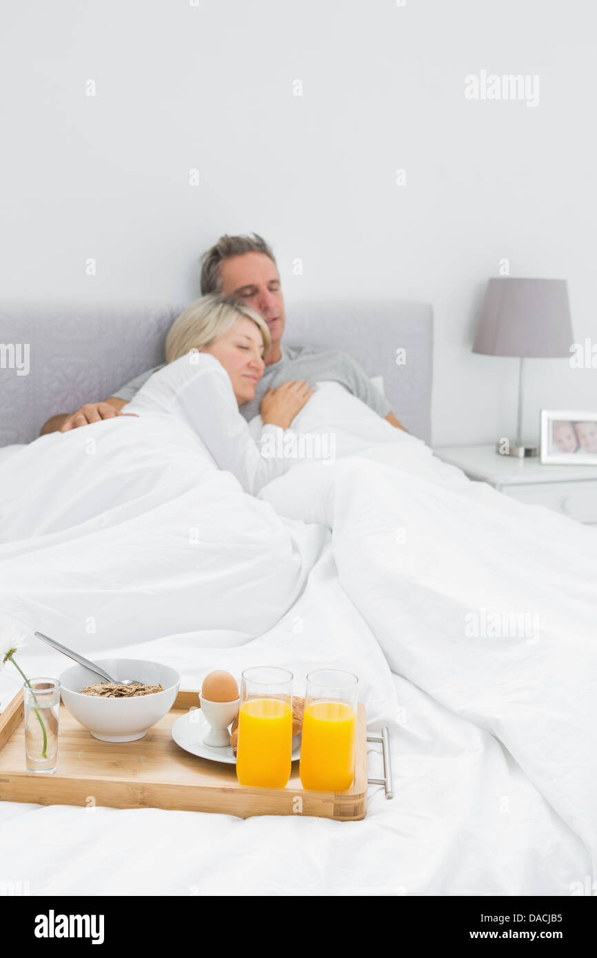 Couple sleeping with breakfast tray at end of bed Stock Photo Alamy