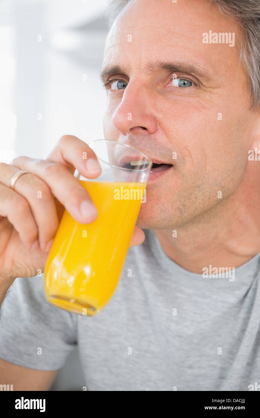 Cheerful man drinking orange juice in kitchen Stock Photo Alamy