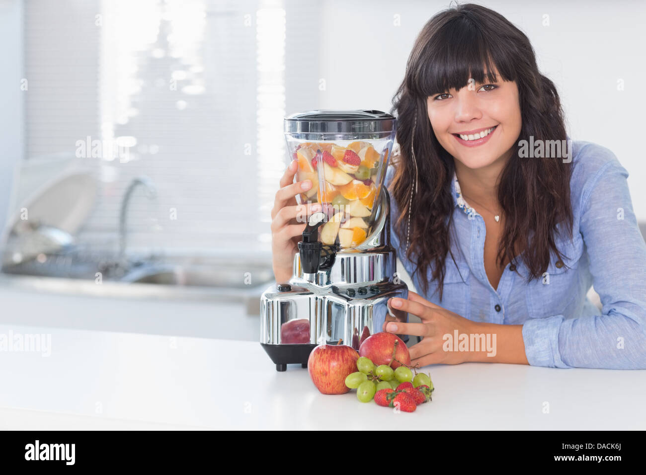 Happy brunette with juicer full of fruit Stock Photo