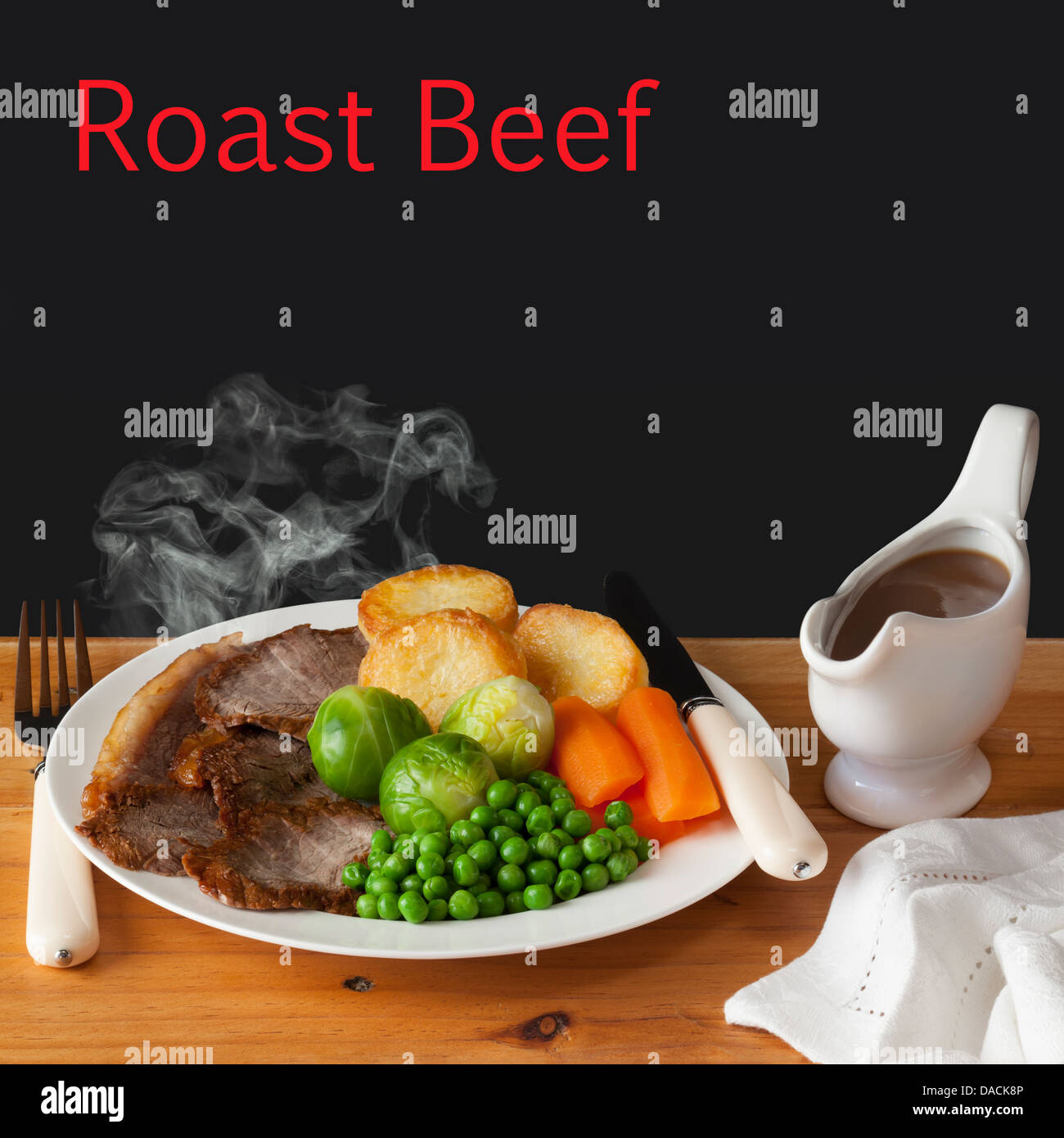 Roast Beef Concept - steaming hot roast beef with roast potatoes, brussels sprouts, carrots, peas and a jug of gravy... Stock Photo