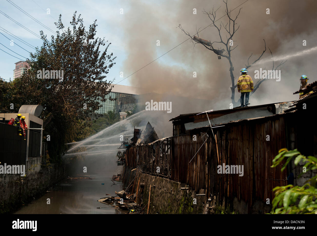 Firemen hose down a fire in a shanty town in Makati City, Metro Manila ...