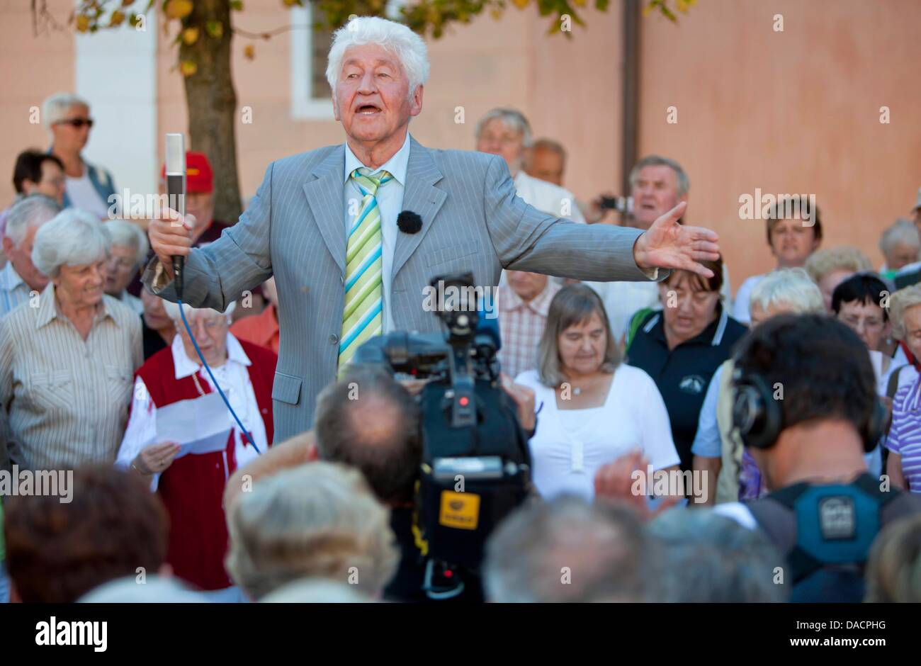 Choir leader Gotthilf Fischer (C) stands surrounded by a crowd singing folk songs on the market square in Eisenach, Germany, 30 September 2011. The event marks the prelude to the televised live event 'Die schoensten deutschen Volkslieder' (The most beautiful German folk songs) of German broadcasting station MDR, which nominates the most favourite song. Photo: Michael Reichel Stock Photo