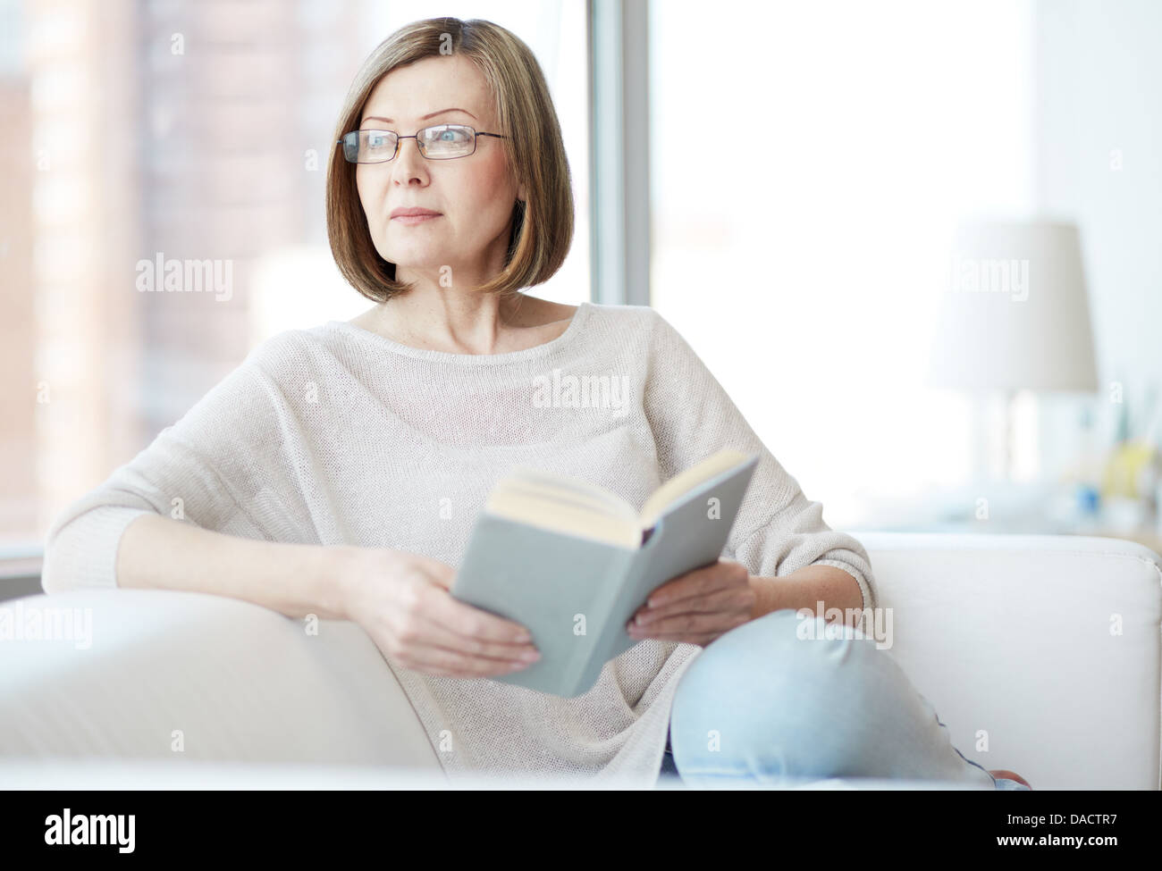 Charming mid age lady enjoying being at home and reading Stock Photo