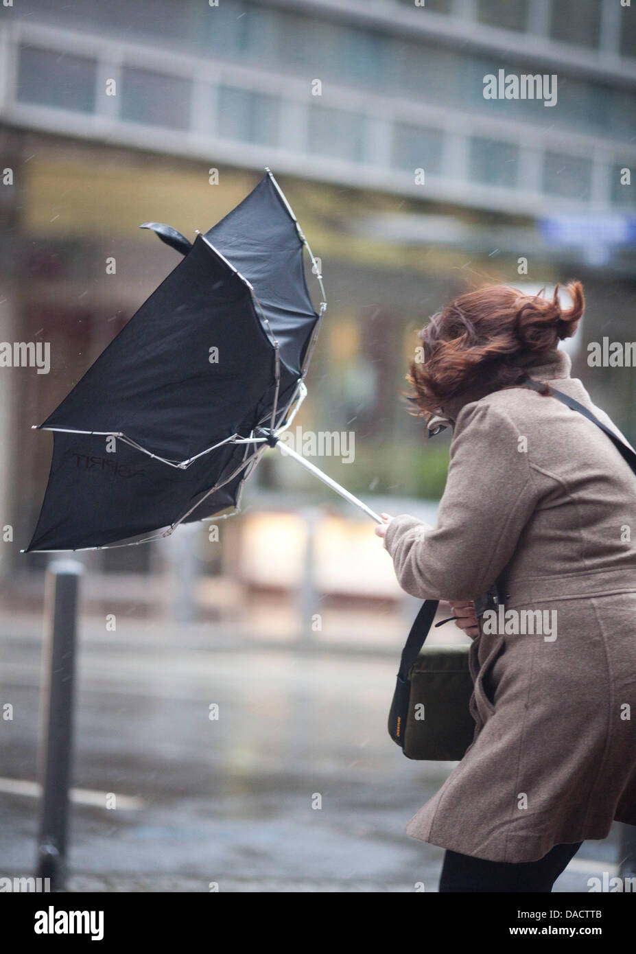 A woman tries to hold on to his umbrella during stormy weather in the city center of Frankfurt Main, Germany, 16 December 2011. Intense low-pressure system 'Joachim' brings chaotic weather conditions to Germany. Photo: Frank Rumpenhorst Stock Photo