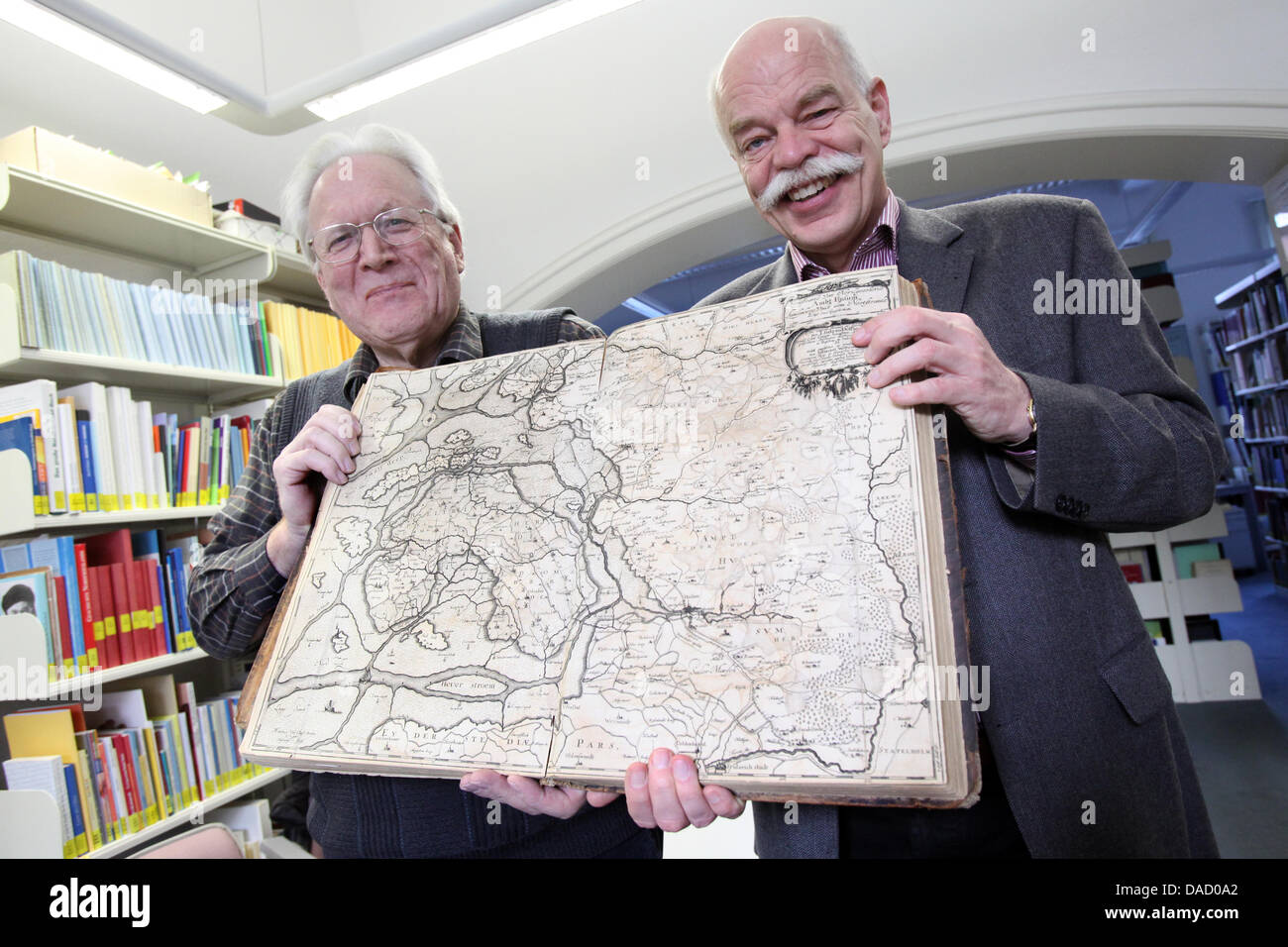 (FILE) An archive photo dated 09 December 2011 shows North Frisian historian Albert Panten (L) and director of the Nordfriisk Instituut, Prof. Thomas Steensen holding a book with a map with a the image of the reconstruction of the coastal area of North Frisia after the 'Grote Mandrenke' ('Great Drowning of Men') of 1362 in Bredstedt, Germany. The reconstruction was created by illus Stock Photo