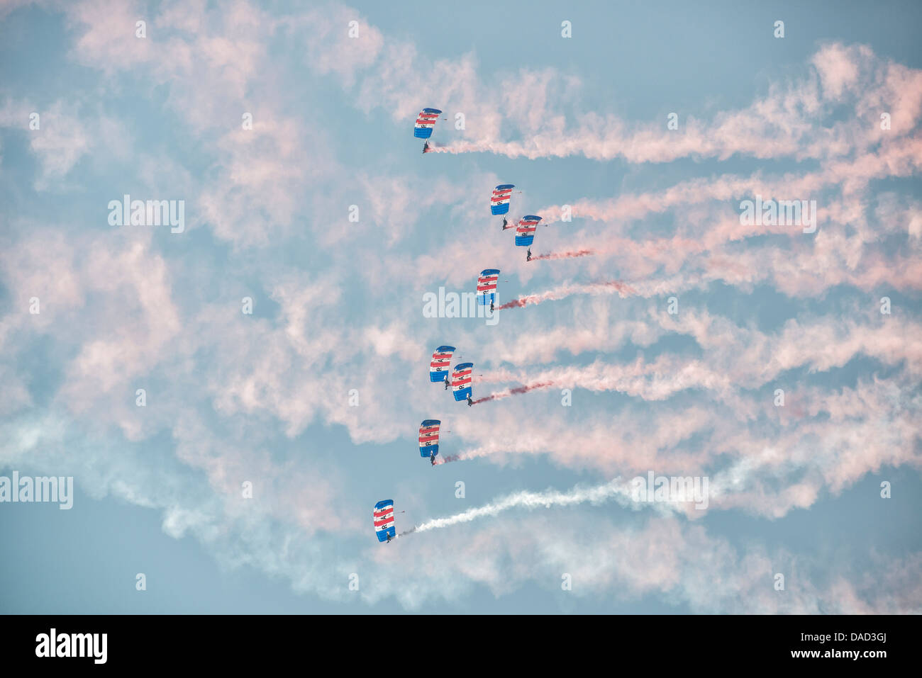 Skydivers from the Royal Air Force Falcons display team fill the sky with their colourful parachute canopies and smoke trails. Stock Photo