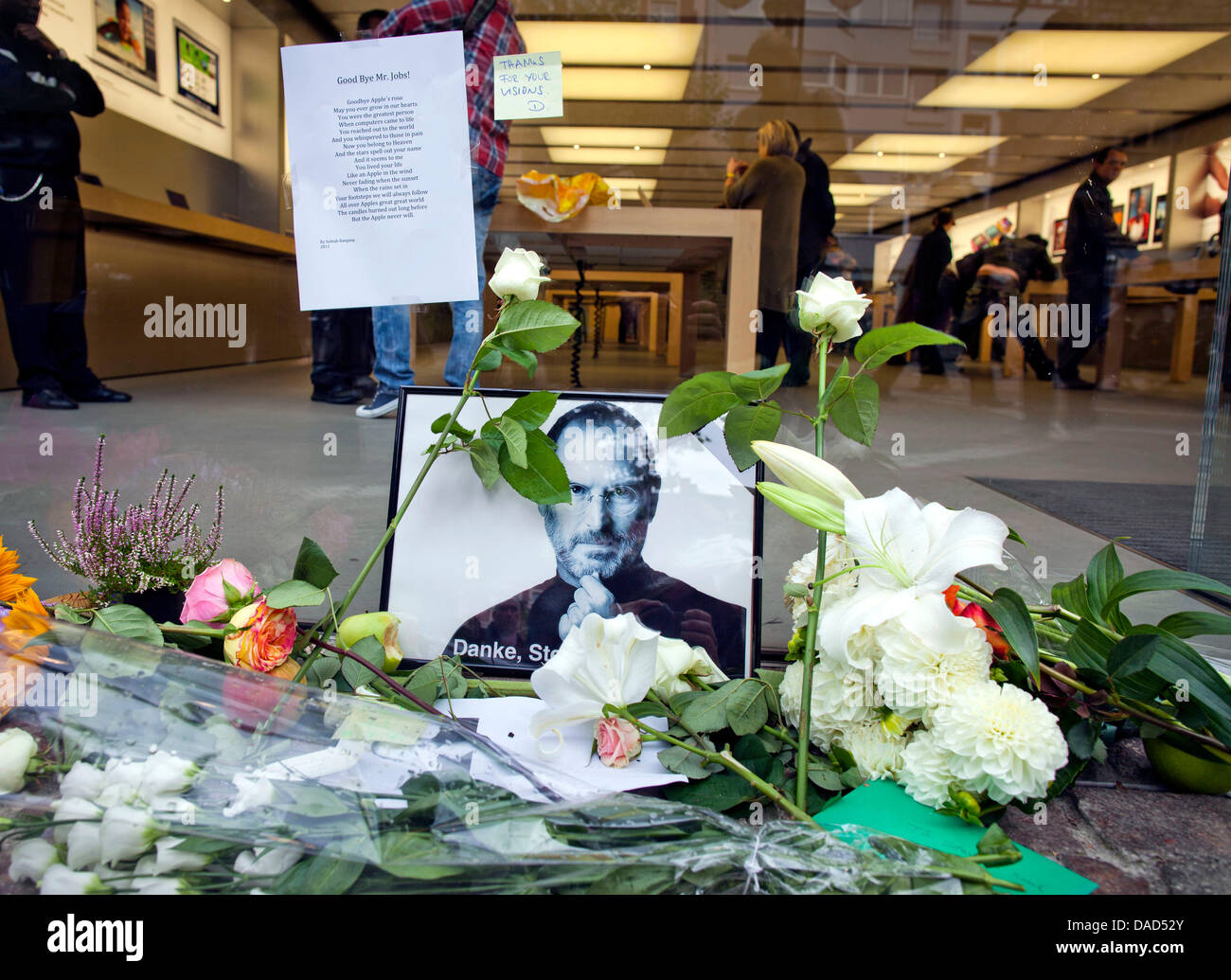 Flowers and a portriat of the cofounder of Apple Steve Jobs are lain in front of the Apple