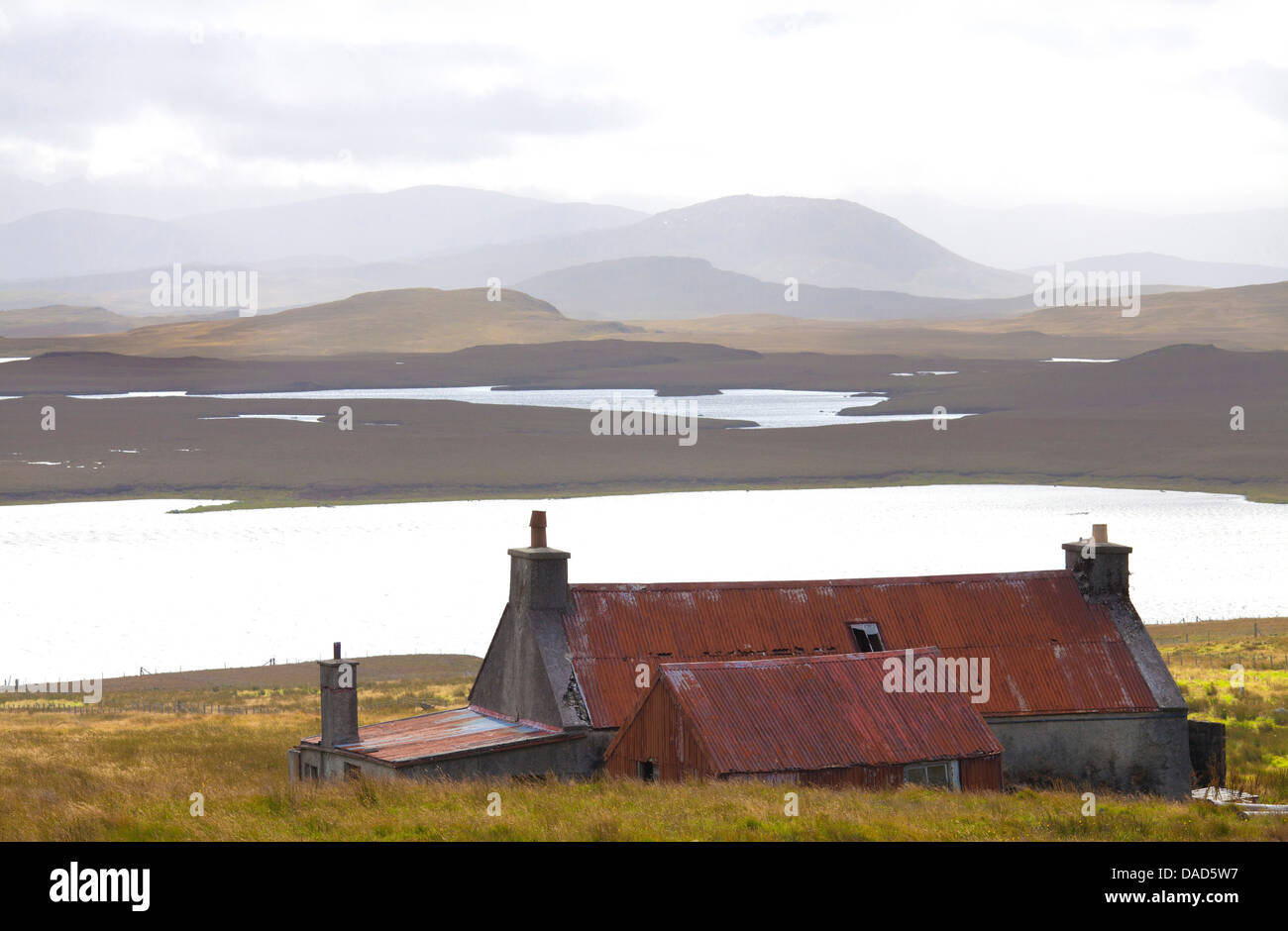 Farmhouse with red iron roof overlooking lochs and mountains off the A858 south of Carloway, Isle of Lewis, Scotland, UK Stock Photo