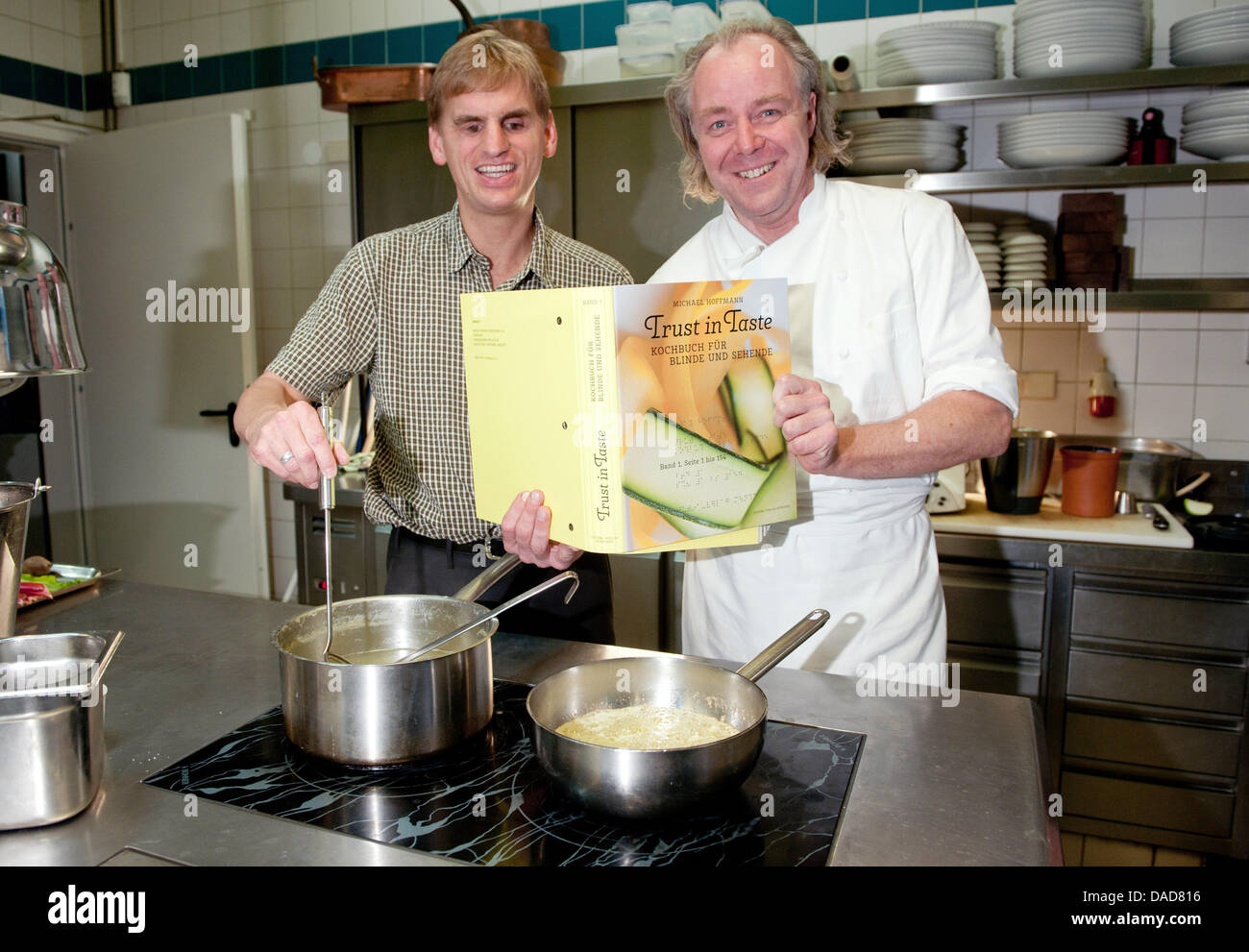 The blind hobby chef Hans Maier (L) and the Michelin-starred chef Michael Hoffmann pose during the presentation of the cookbook  'Trust in Taste - Kochbuch fuer Blinde und Sehende' ('Cookbook for blind and sighted persons') inside the kitchen of the restaurant Margaux in Berlin, Germany, 11 October 2011. The recipes are printed in black letters for sighted readers as well as in con Stock Photo