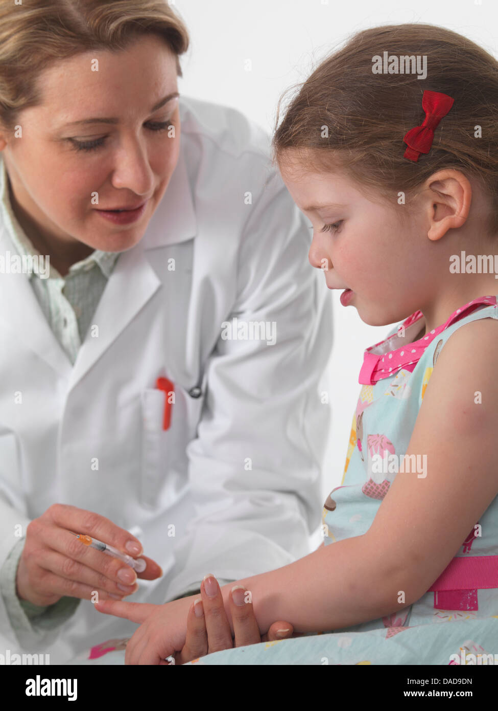 General practice doctor vaccinating a small girl in surgery Stock Photo